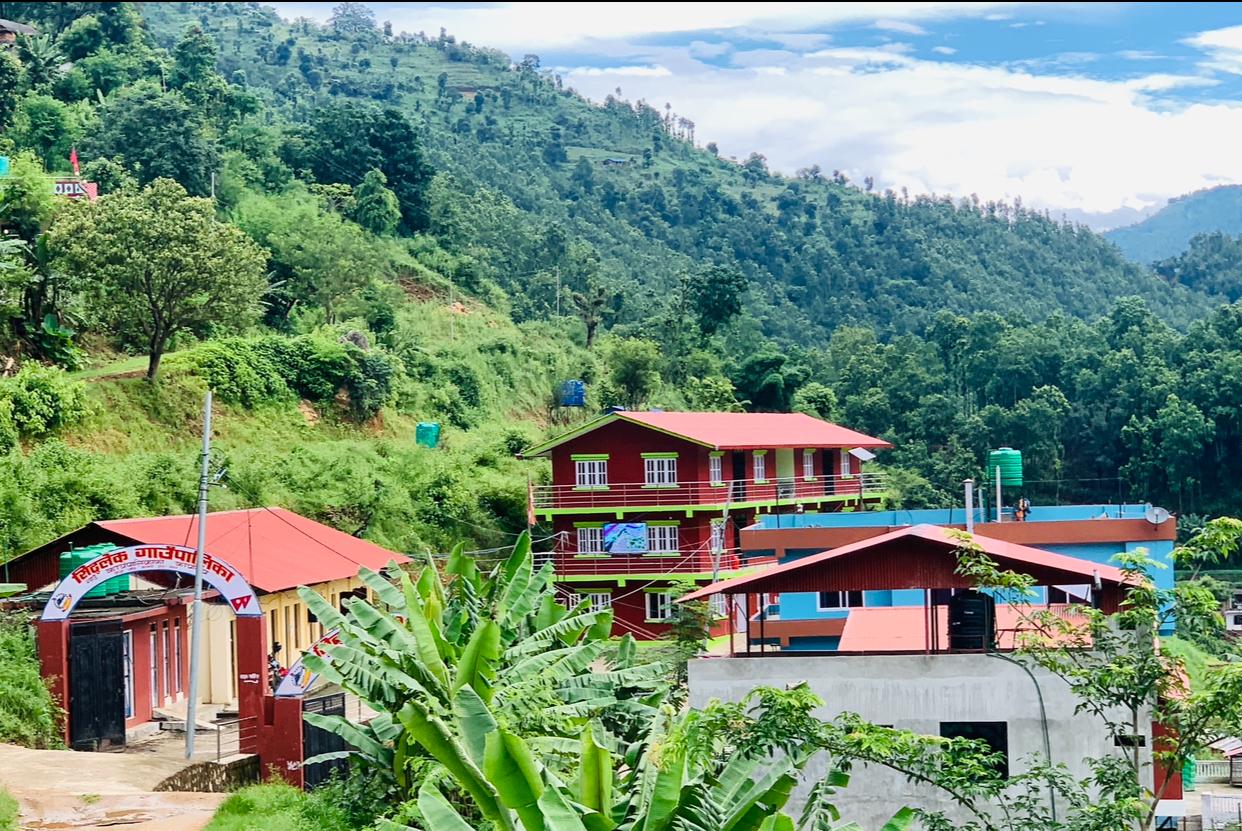 View of the Siddhalek Rural Municipality office premises surrounded by lush green hills and natural landscape in Dhading, Nepal.